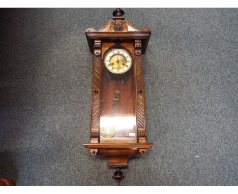 A Vienna-styled wall clock, walnut case with opening glazed door flanked by geometric decoration, surmounted by an architectu