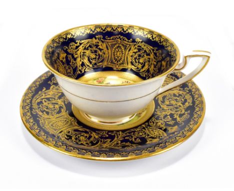 ROYAL WORCESTER; a floral painted and gilt heightened cabinet cup and saucer signed by Ernest Barker, puce marks to base, dia