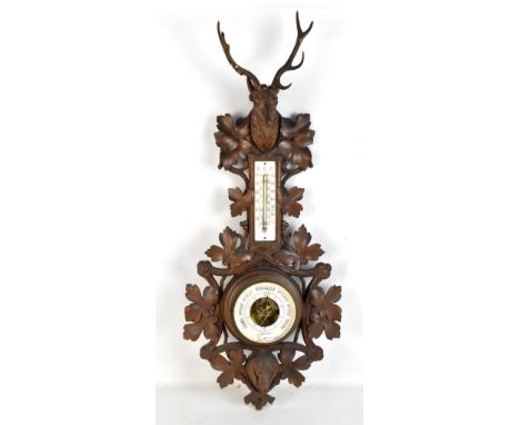 A c1900 stained beech Black Forest thermometer/barometer with stag's head above leaf carved frame, thermometer dial, baromete