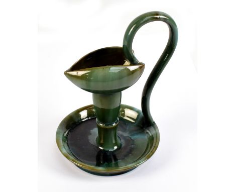 An art pottery chamber stick in the style of Linthorpe with high loop handle and green glazed body, unmarked, height 18.75cm.