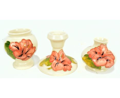 MOORCROFT; two tubeline decorated 'Hibiscus' pattern vases and a single candlestick (af), all on cream grounds with impressed