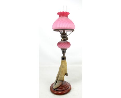 A silver plated candlestick on taxidermy hoof base with a pink glass oil lamp conversion, height 59cm.Additional InformationS