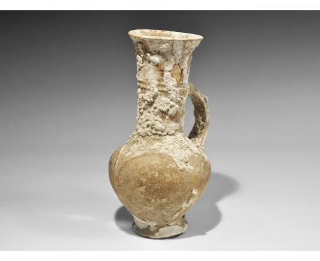 1650-1050 BC. A tall ceramic Cypriot jug with flared base, tall neck, everted rim, single strap handle; relief decoration of 