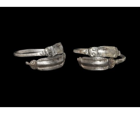 3rd-4th century AD. A square-section coiled silver bar with D-section finials, each a plaque with eyes and muzzle at each end