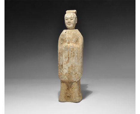 Northern Qi Dynasty, 550-577 AD. A hollow-cast ceramic figurine of an attendant in long robe, hands drawn up the chest; pierc