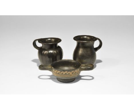 4th century BC. A mixed group of ceramic blackware vessels comprising: a jug with flared rim and loop handle; a skyphos with 