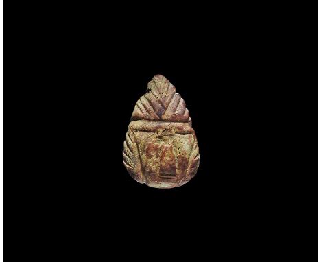 5th century BC. A carved amber pendant, triangular in form and pierced at the narrow end; trapezoidal face framed by three tr