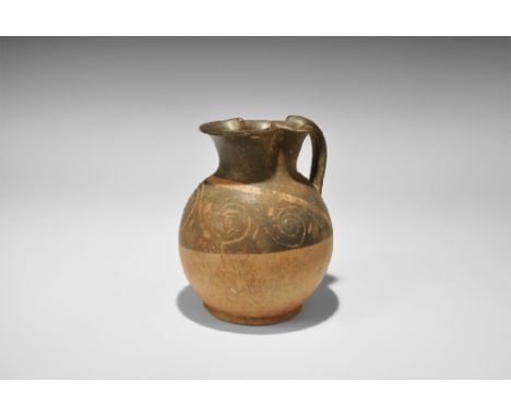 4th century BC. A blackware ceramic oinochoe with bulbous body and flared rim to the foot, deep trefoil rim and strap handle 