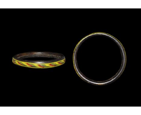 1st-3rd century AD. An annular rectangular-section dark red glass bangle with marvered twisted trails of yellow, green and re