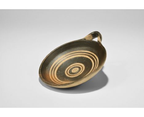 4th century BC. A convex ceramic dish with concentric ring ornament, applied strap handle to the rim.    114 grams, 14cm (5 1