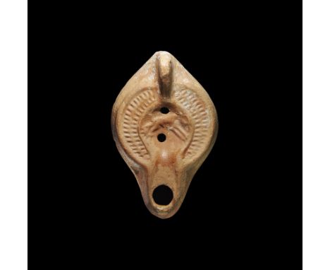 1st-2nd century AD. A terracotta lamp with broad body, basal ring, D-shaped nozzle, lug handle to the rear; the discus with o