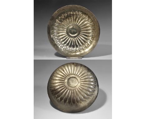 4th century BC. A deep silver bowl with carinated wall and everted rim, decorated with repoussé lotus leaves and raised centr