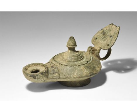 4th century AD. A hollow-cast lamp with flared base, collared nozzle with broad dished spout and segmented collar behind, hin
