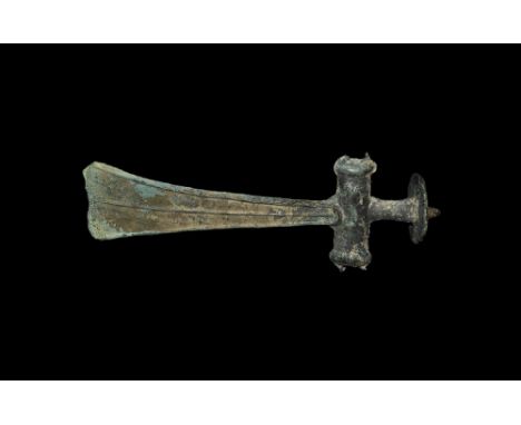 2nd millennium BC. A large facetted triangular bronze blade with straight cutting edge, lateral flanges and median rib, ellip
