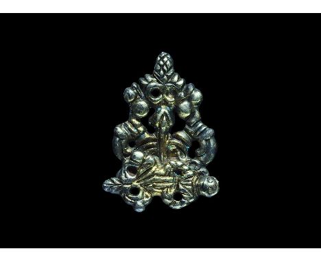 16th-17th century AD. A silver triangular clothes fastener with openwork detailing of fruit and tendrils; to the lower edge a