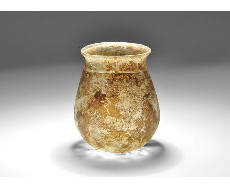 3rd-4th century AD. A broad amber glass jar with dimple base, everted rim and applied trail above the shoulder. Cf. Whitehous