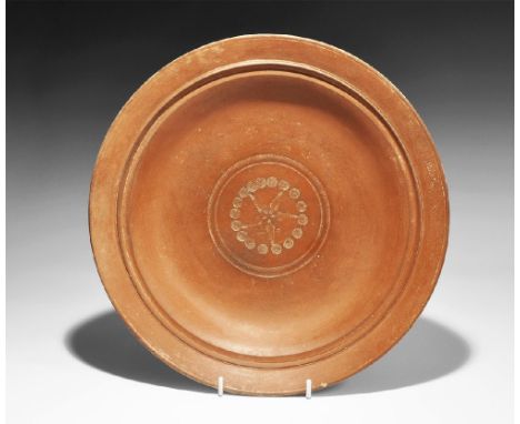4th century AD. A large redware ceramic dish with carinated profile, flared rim, ring of radiating slashes to the inner face 