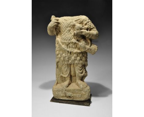 1st-4th century AD. A carved schist statue of a standing warrior on a rectangular block with a bird held in the crook of his 