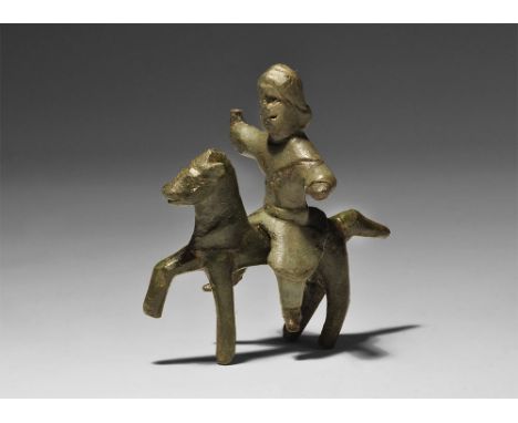 1st century BC-1st century AD. A bronze figurine comprising: a horseman with belted tunic, flowing hair, legs spread and righ