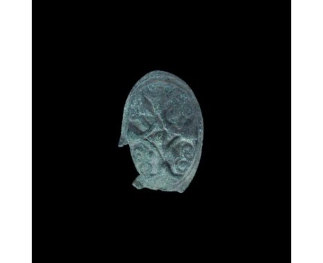 7th-10th century AD. A bronze oval brooch with raised lozenge motif and radiating scrolled tendrils, flared carinated rim, ba