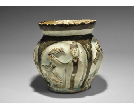 10th-12th century AD. A globular white-glazed ceramic jar with flared rim; the body with sculpted figures within an arcade, t