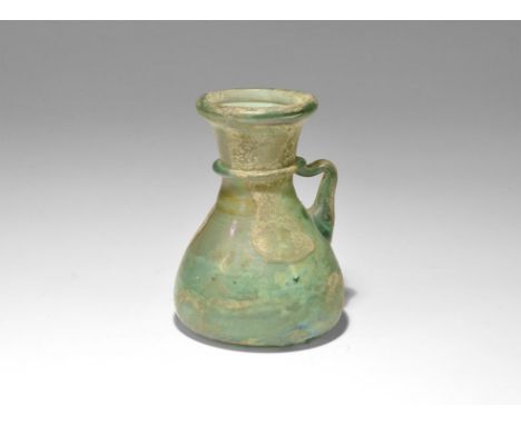 2nd-3rd century AD. A conical green glass flask with dimple to the underside, flared neck and rolled rim; applied trail to th