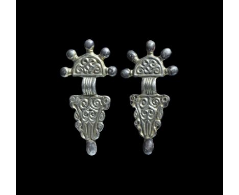 Late 5th-6th century AD. A matched pair of silver-gilt bow brooches, each a D-shaped headplate with scroll ornament, five rad