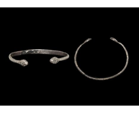 1st-2nd century AD. A D-section silver bracelet with stamped scale detailing, the finials formed as snake-heads with pellet e