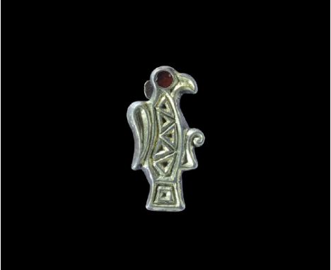 6th century AD. A silver-gilt plate brooch of a stylised bird with chip-carved detail to the wing and body, coiled claw, inse