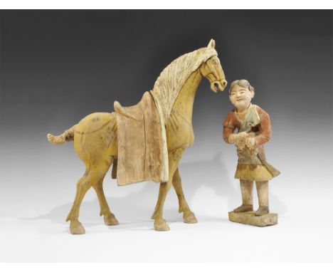 Tang Dynasty, 618-906 AD. A pair of ceramic figurines comprising: a standing horse with mouth open, legs straight, saddle cov