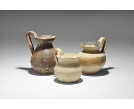 4th century BC. A mixed group of ceramic vessels comprising: a redware jug with strap handle; a buffware jug with cupped rim,