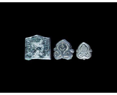 9th-12th century AD. A mixed group of silver mounts, two heart-shaped with scrolled foliage detail and one square with raised