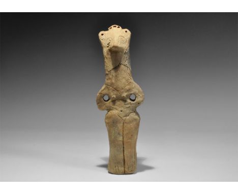 Neolithic, 6th-5th millennium BC. A columnar ceramic figurine with pinched facial features, looped arms, pierced lugs to the 