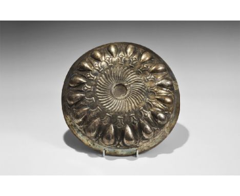 4th century BC. A large silver dish with carinated everted rim, repoussé central boss and piriform panels, fluted surround wi