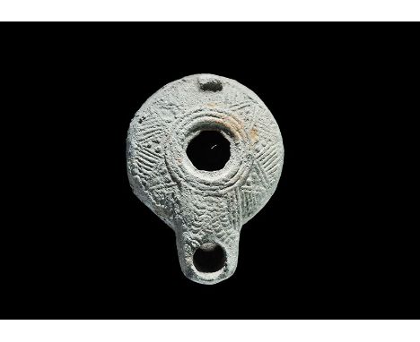 1st-2nd century AD. A squat terracotta oil lamp with radiating hatched triangles to the discus, broad nozzle, stub handle to 