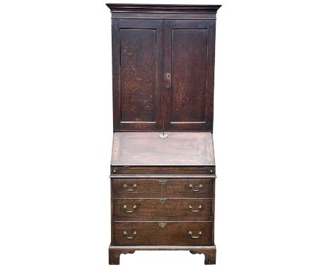 A George III oak bureau bookcase, with a part of panelled doors opening to reveal shelves, above a fall front enclosing a fit
