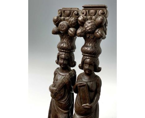 A pair of oak caryatids, circa 1800, carved with standing figures, one playing a lute, above swags, leaves and fruit, height 