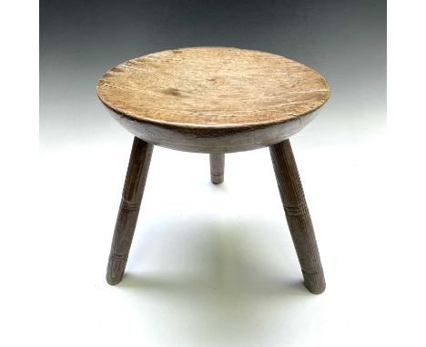 A 19th century sycamore and ash milking stool, with a circular dished seat, on three circular ring turned legs, height 32.5cm