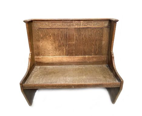 A 1930's oak bench settle, the raised panel back with foliate carved rail, height 115cm, width 121cm.