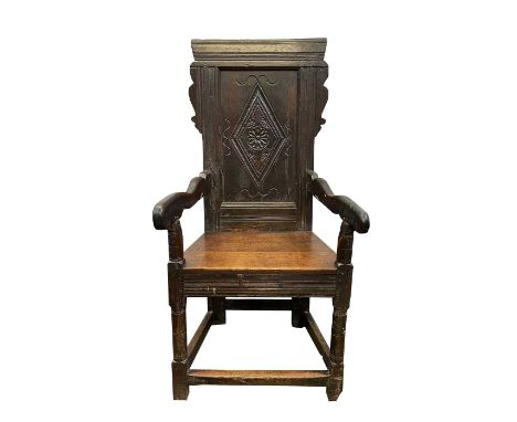 An oak Wainscot armchair, late 17th century, the back with a central carved lozenge motif, solid arms and seat on ring turned