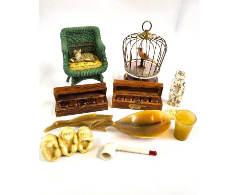 A working musical bird in a cage, a ceramic cat in a wicker chair, bone items, Yahtzee dice, spoons, etc.