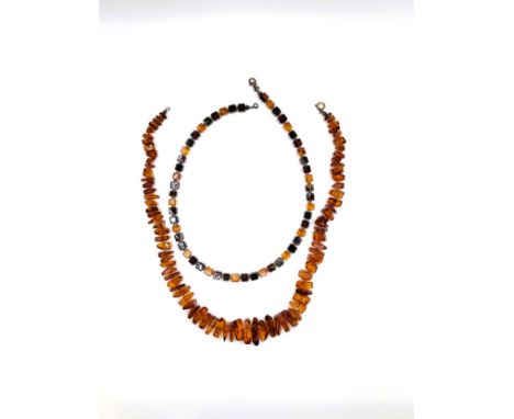 An amber irregular shaped ascending sized necklace with a gold jump ring clasp, 47cm 34.1gms, and an amber cubed necklace on 