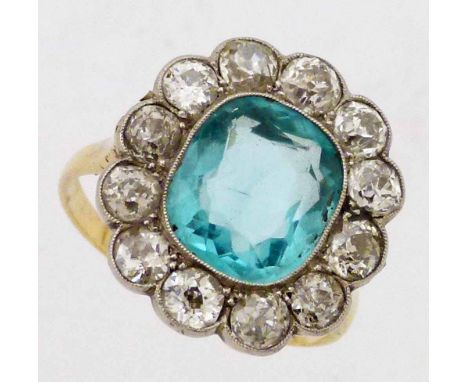 Antique oval cluster ring, the central pale blue stone surrounded by thirteen old European cut diamonds, on an unmarked shank