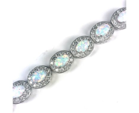 An opal and cubic zirconia line bracelet in Sterling Silver designed as seventeen oval opal and CZ clusters. Length 18cm / 7"