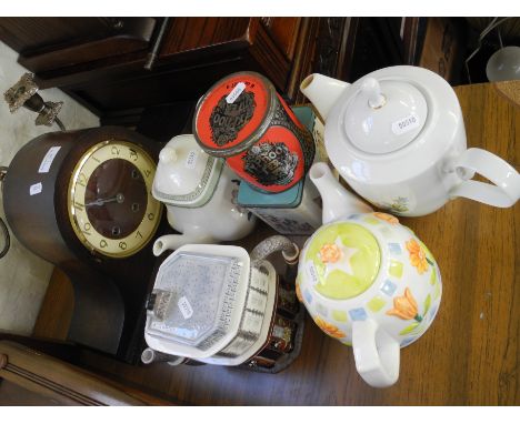 A mantle clock, four teapots, two collectible tins.
