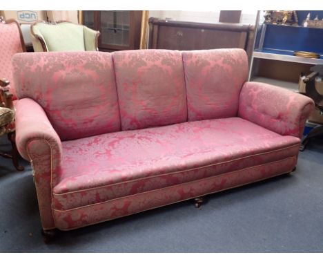 A COUNTRY HOUSE STYLE THREE-SEATER SOFA the back with three integral cushions, with scrolling arms and bun feet, 196cm wide (