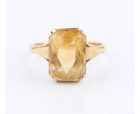 A citrine dress ring, set with an emerald cut citrine, measuring approx. 14x10mm, with raised shoulders, set in unmarked yell