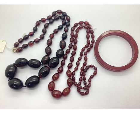 A Cherry Coloured Beaded Necklace, oval beads of graduated size, knotted, together with a cherry coloured bangle, and a state