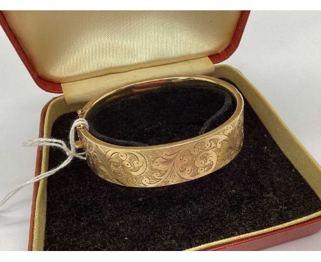 A Vintage 9ct Gold Wide Bangle, the hinged front with etched scrolling foliage design, to push clasp with safety chain, in a 