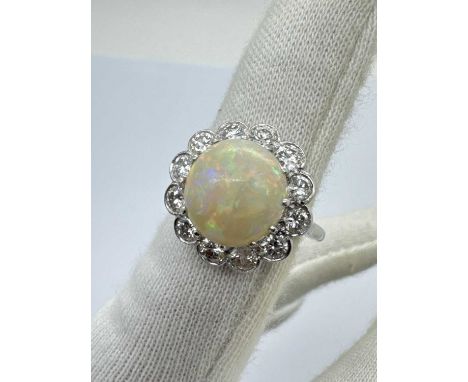 A Large Opal and Diamond Cluster Ring, the central circular cabochon opal claw set within shaped border of brilliant cut diam